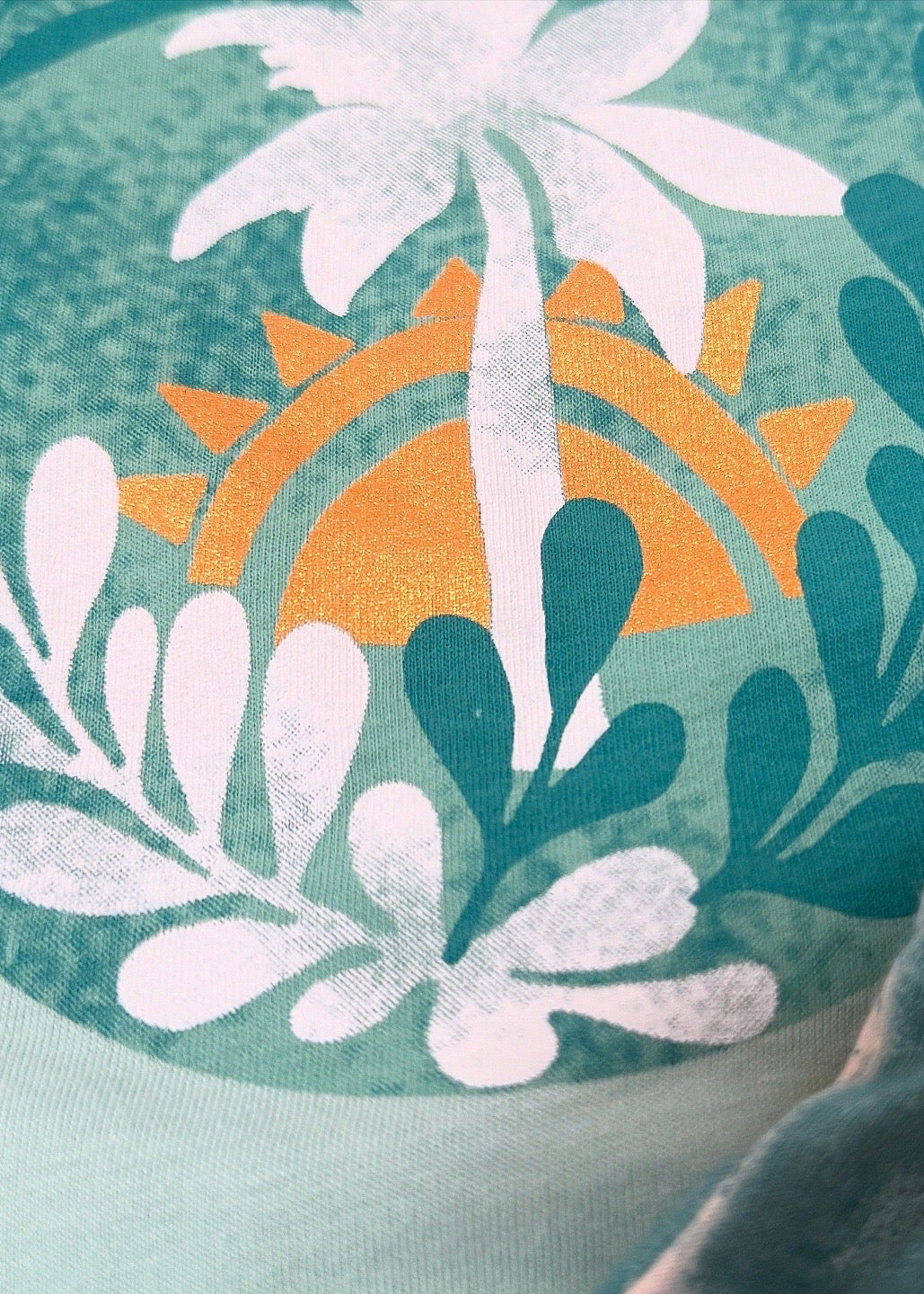 Fabric with a tropical design featuring a palm tree, sun, and leaves on a green background.