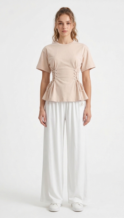 Woman wearing a beige top and white pants on a white background
