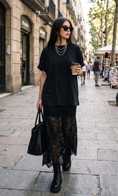 Woman in black outfit with lace skirt walking on a city street.