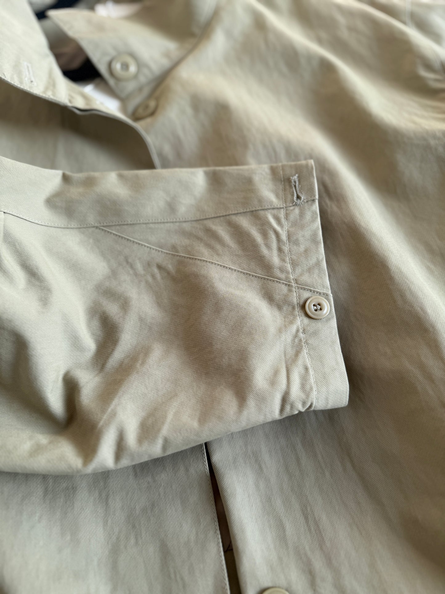 Close-up of beige pants with a pocket and button details.