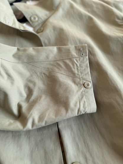 Close-up of beige pants with a pocket and button details.