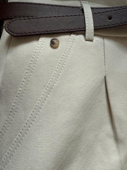Close-up of beige pants with a button and gray belt