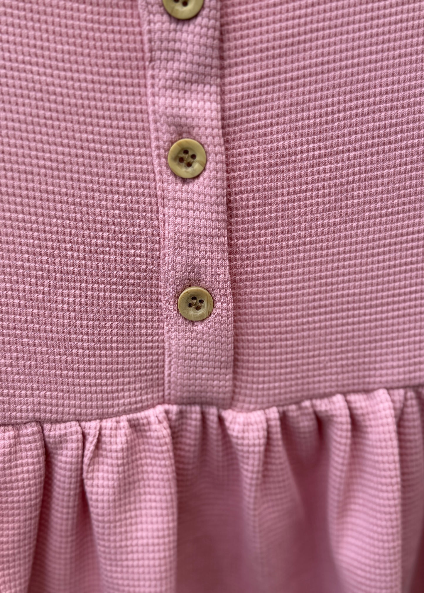 Close-up of a pink garment with button details