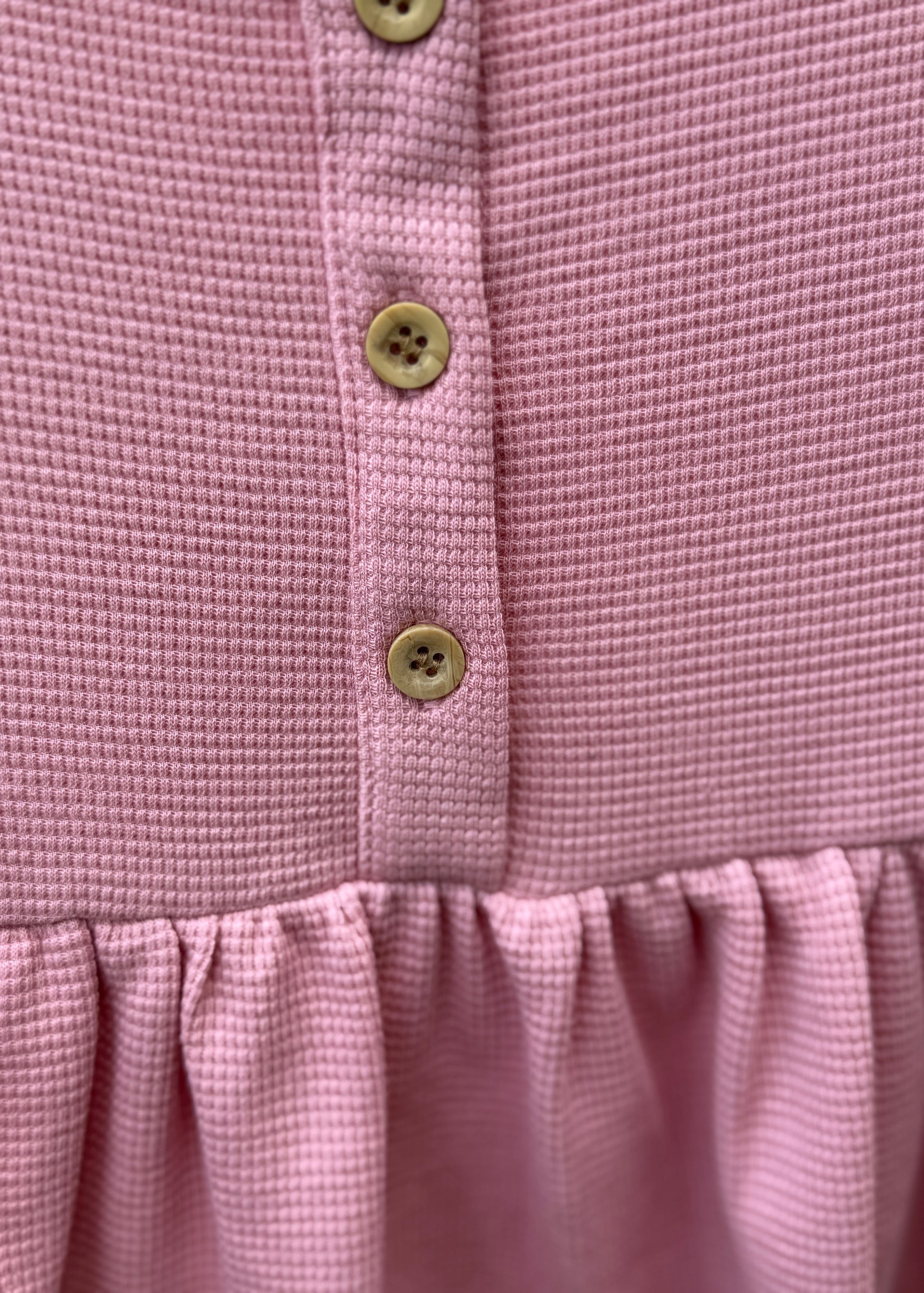 Close-up of a pink garment with button details