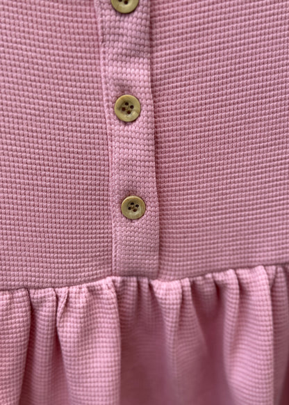 Close-up of a pink garment with button details