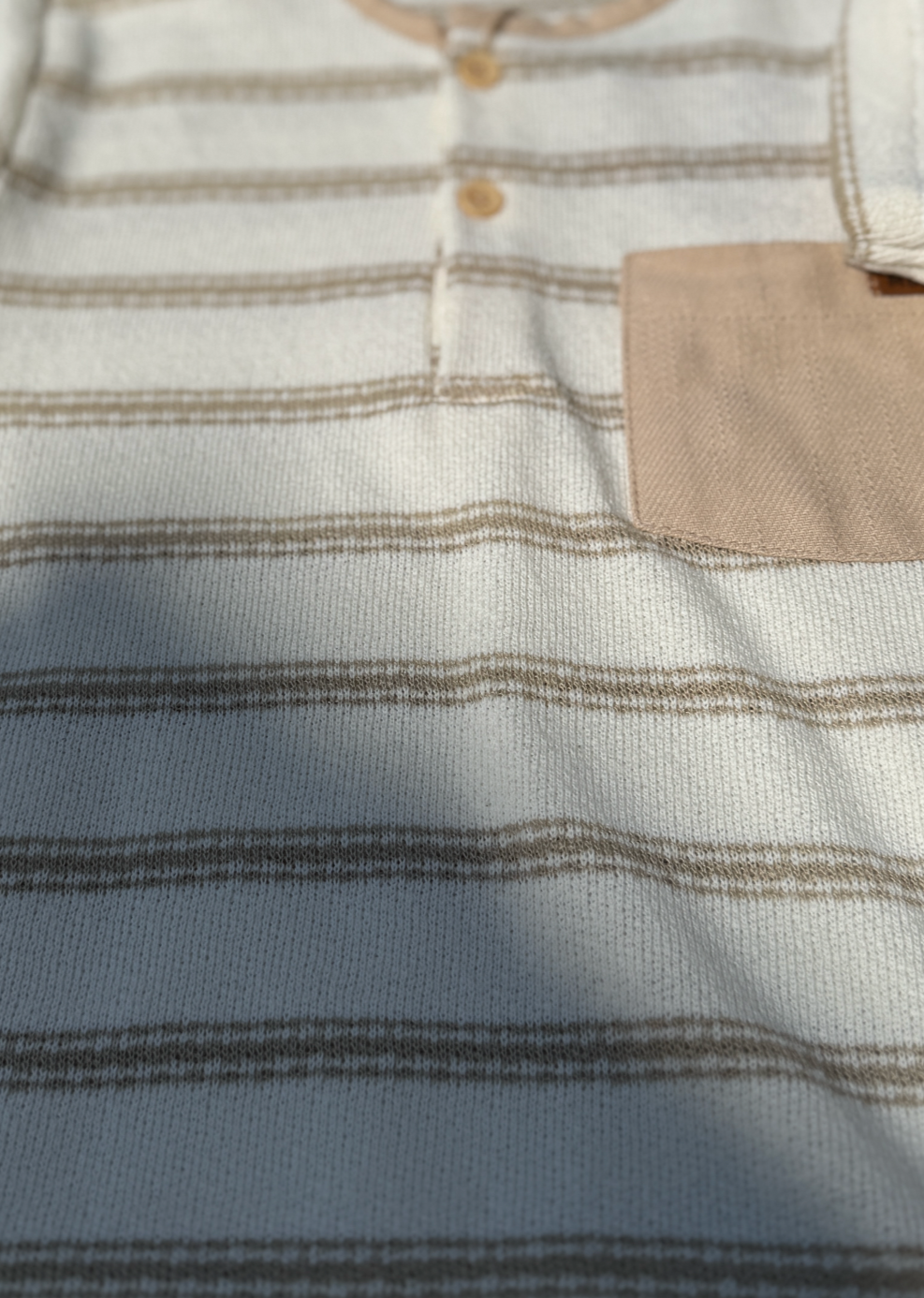 Close-up of a striped shirt with a pocket and buttons.