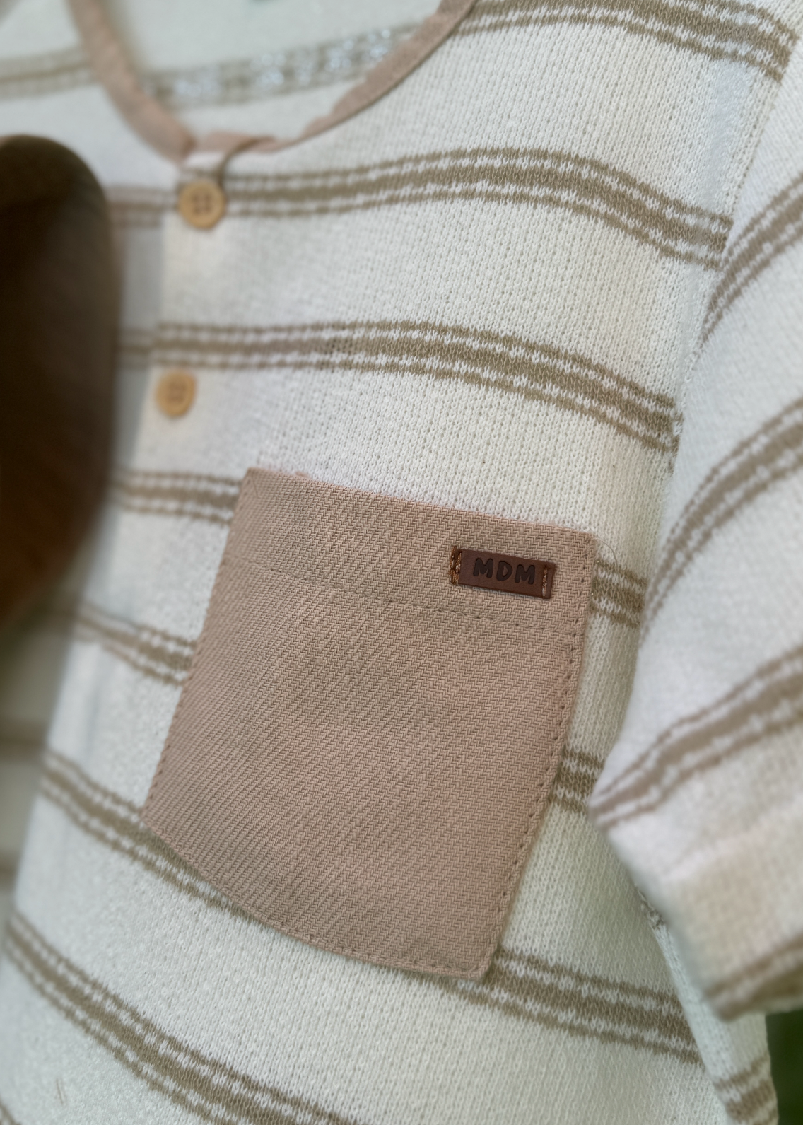 Close-up of a baby outfit with a label on a neutral background