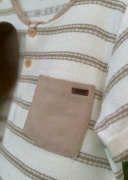 Close-up of a baby outfit with a label on a neutral background