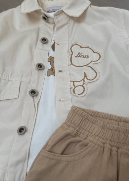 Beige jacket with embroidered bear design and brown pants on a neutral background