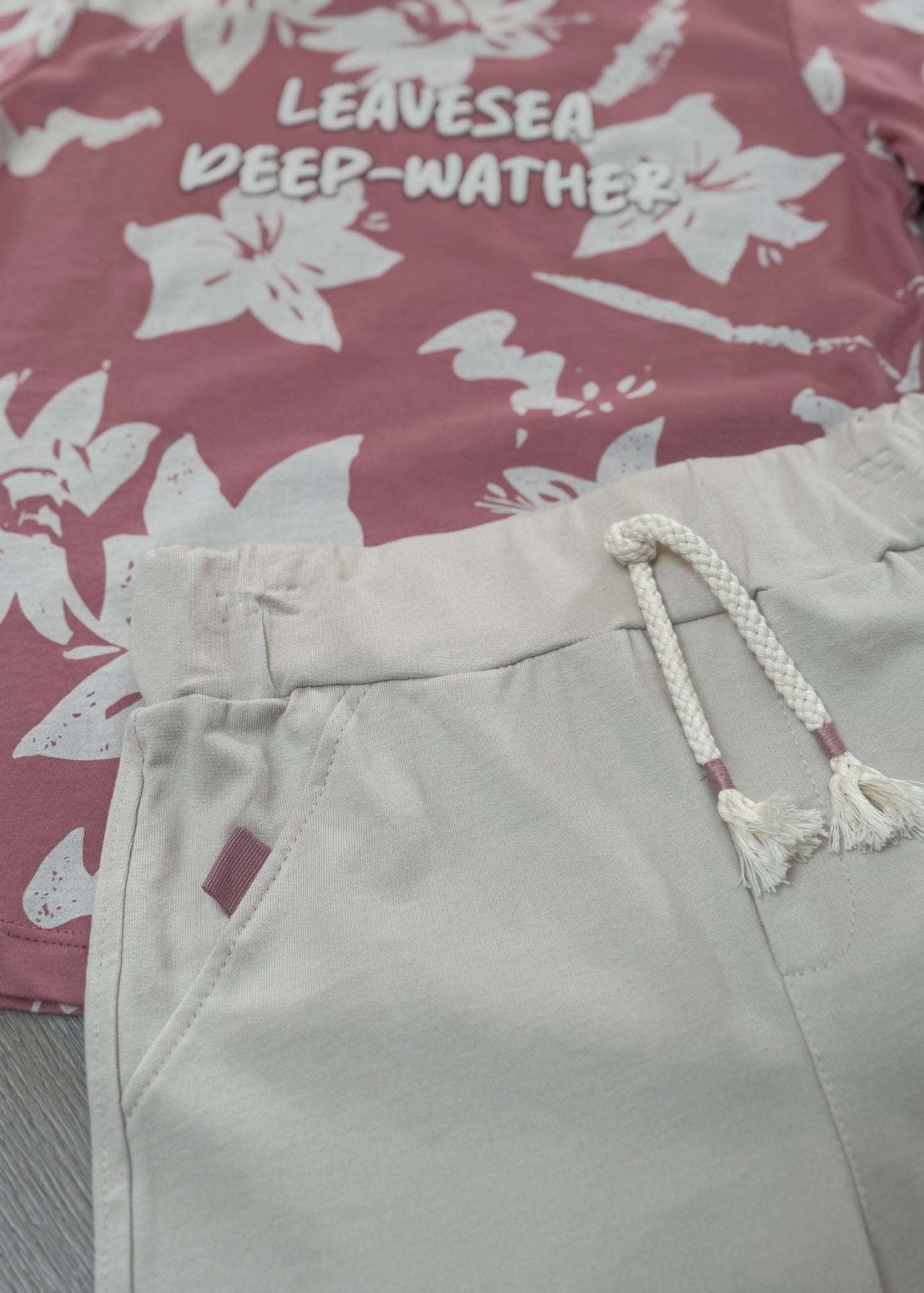 Light gray shorts with a rope drawstring on a floral-patterned fabric background