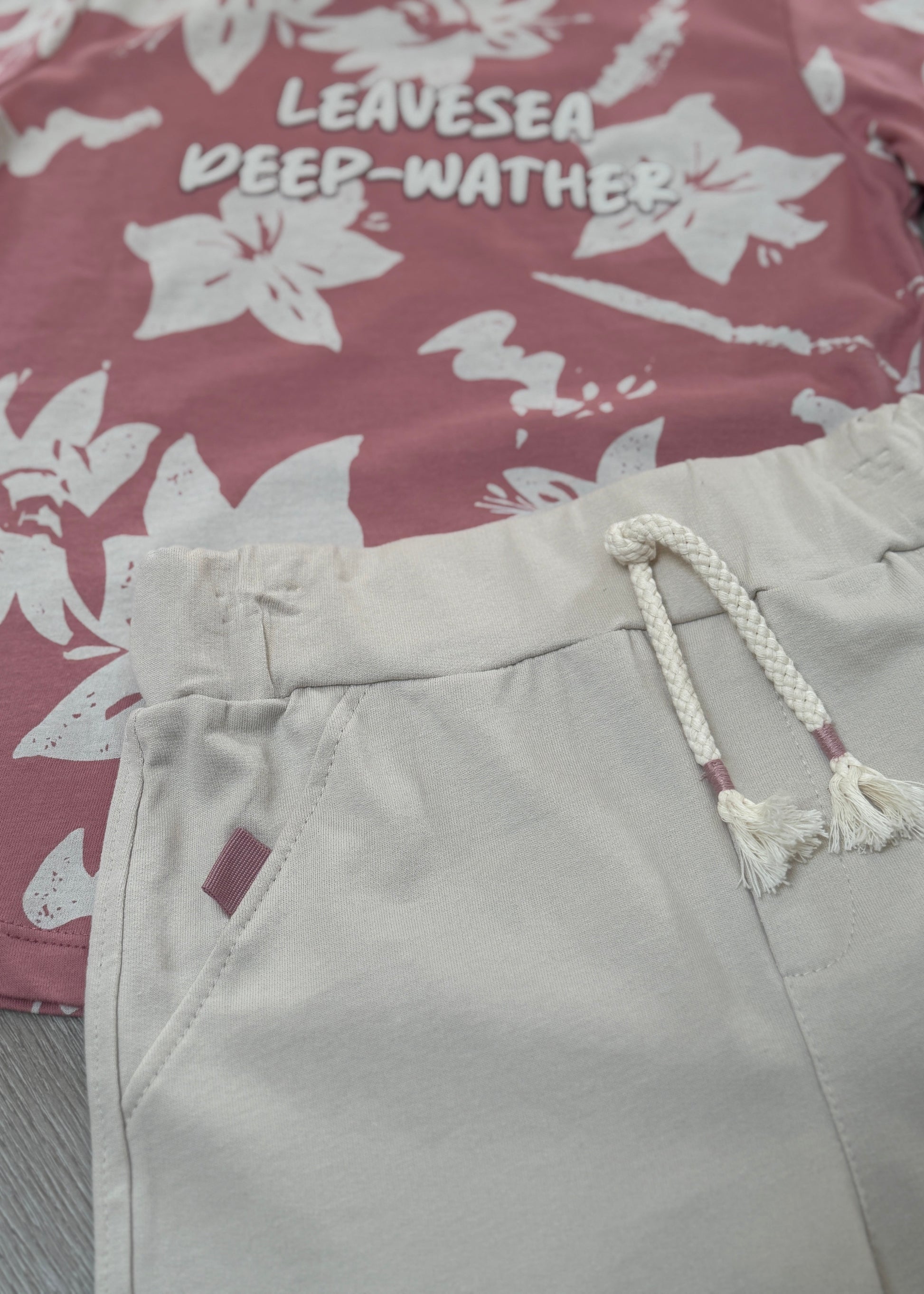 Light gray shorts with a rope drawstring on a floral-patterned fabric background