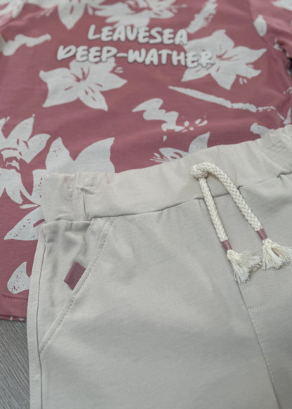 Light gray shorts with a rope drawstring on a floral-patterned fabric background