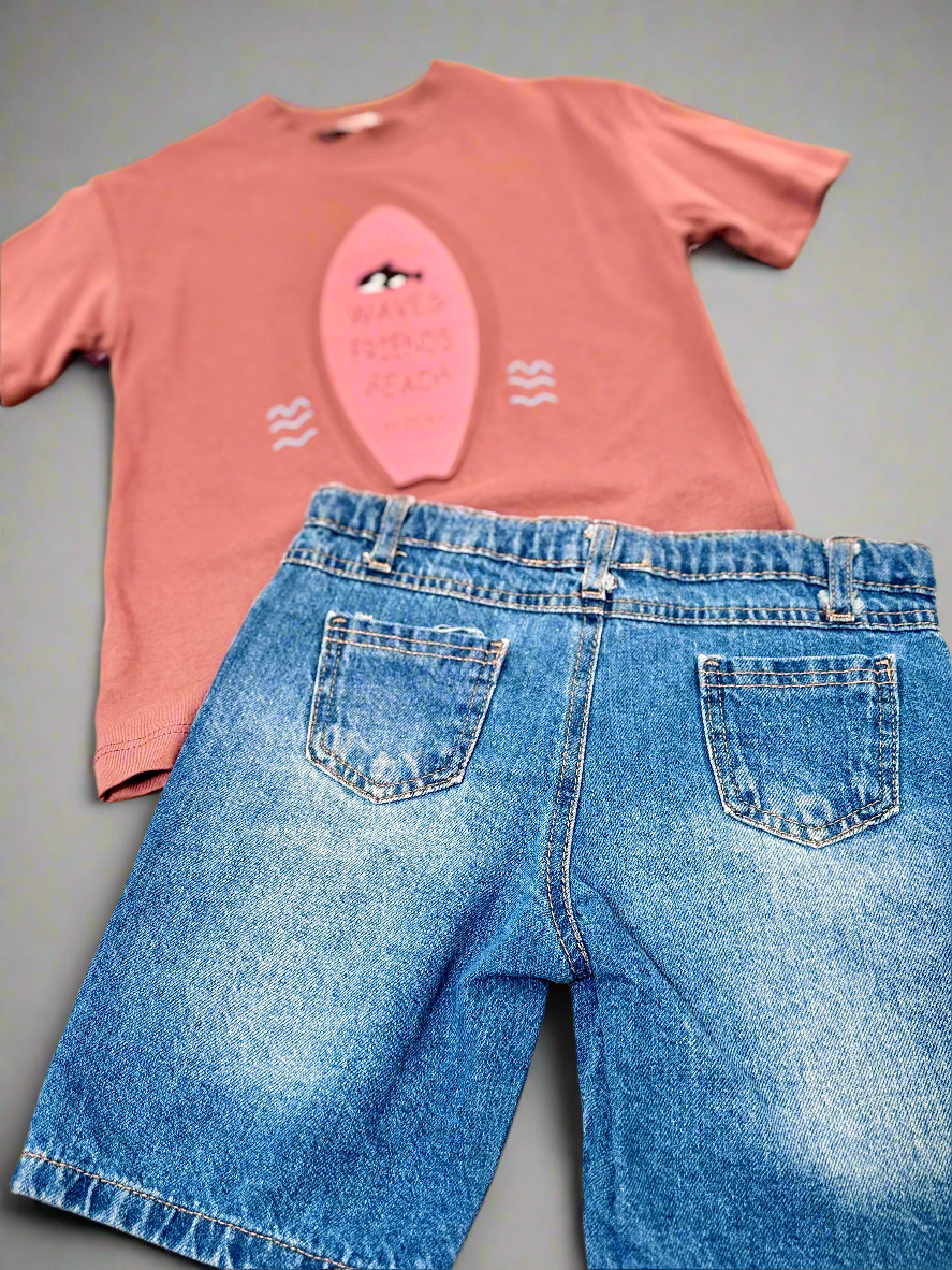Pink t-shirt with a graphic design and blue jeans on a gray background