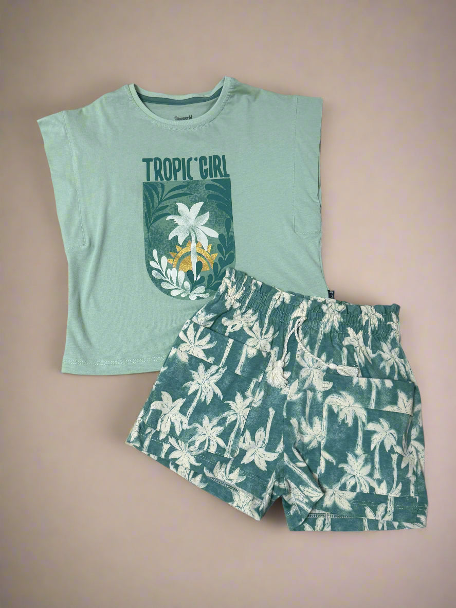 Green t-shirt with 'Tropic Girl' text and floral design, paired with green shorts with white floral pattern on a beige background.