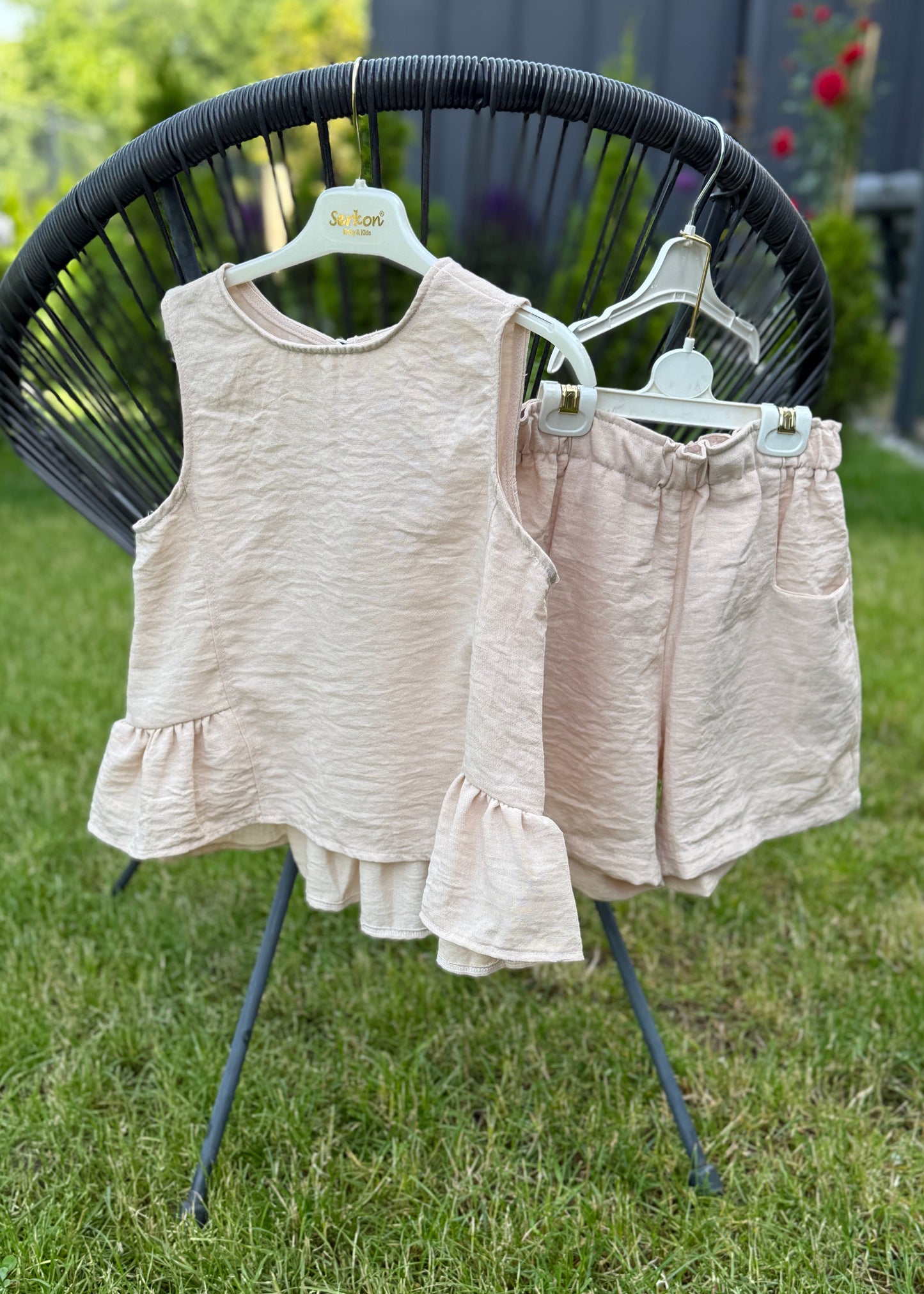Children's sleeveless top and shorts set on a stand outdoors.