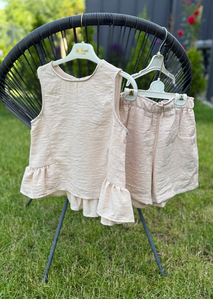 Children's sleeveless top and shorts set on a stand outdoors.