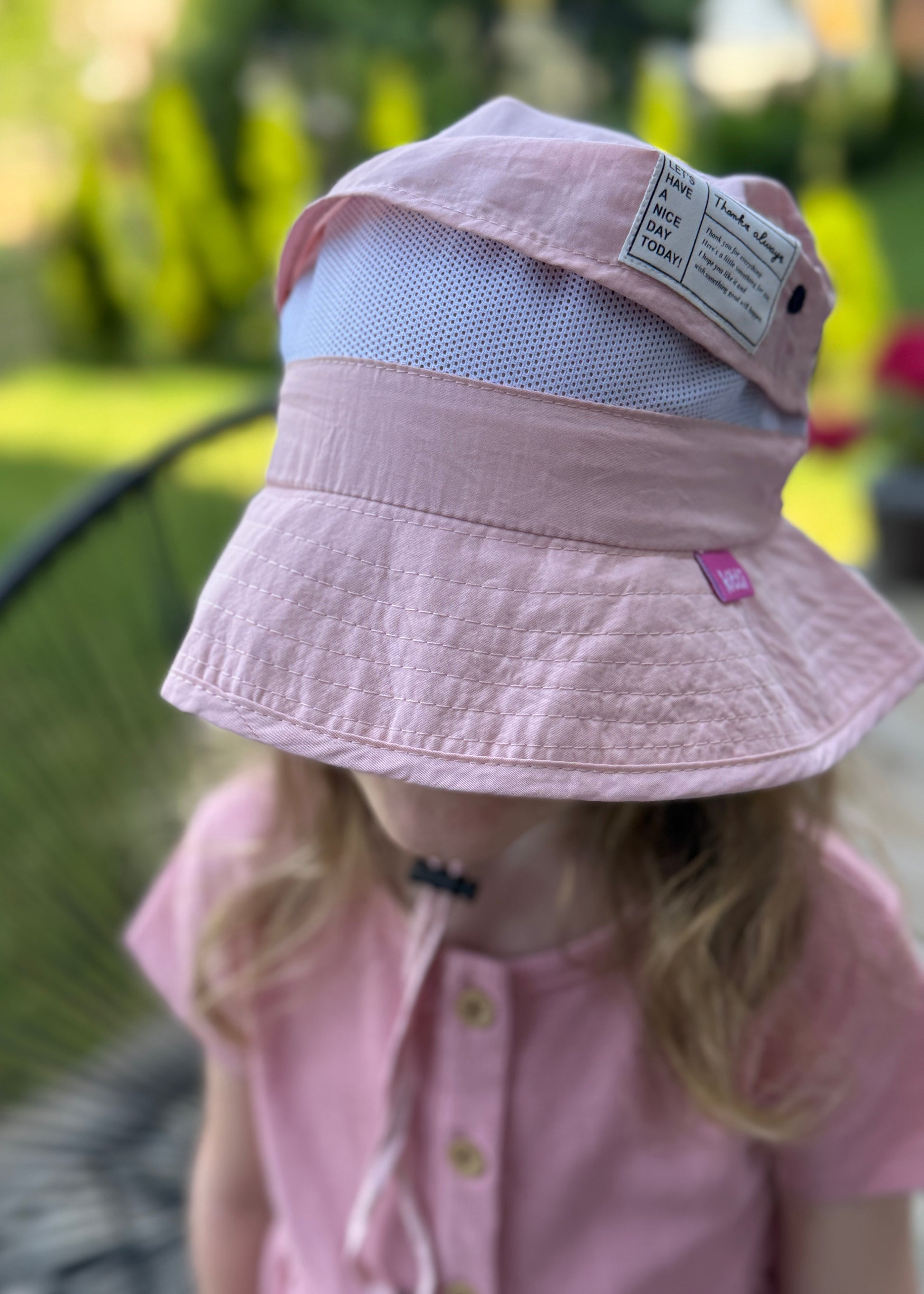 Child wearing a pink sun hat with a mesh back outdoors