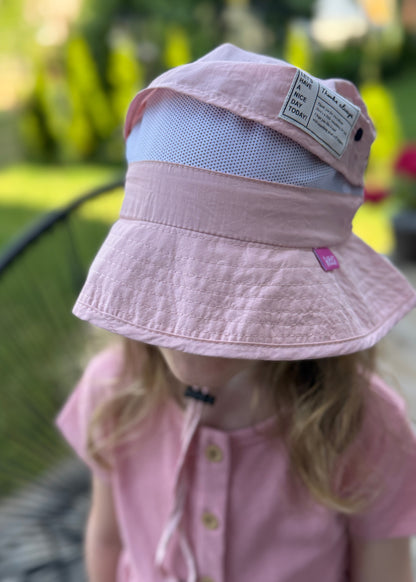 Child wearing a pink sun hat with a mesh back outdoors