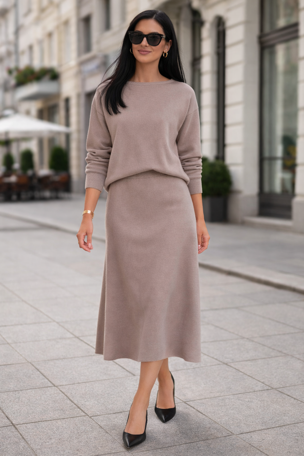 Woman wearing a beige sweater and skirt set on a city street.