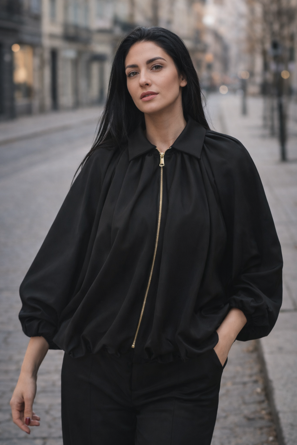 Woman wearing a black jacket with a gold zipper on a city street.