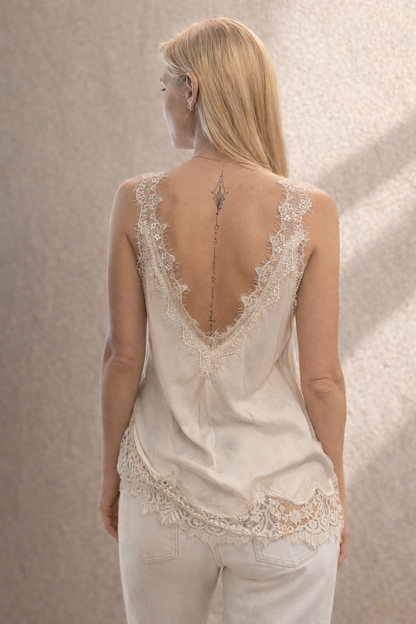 Woman wearing a delicate lace top with a neutral background