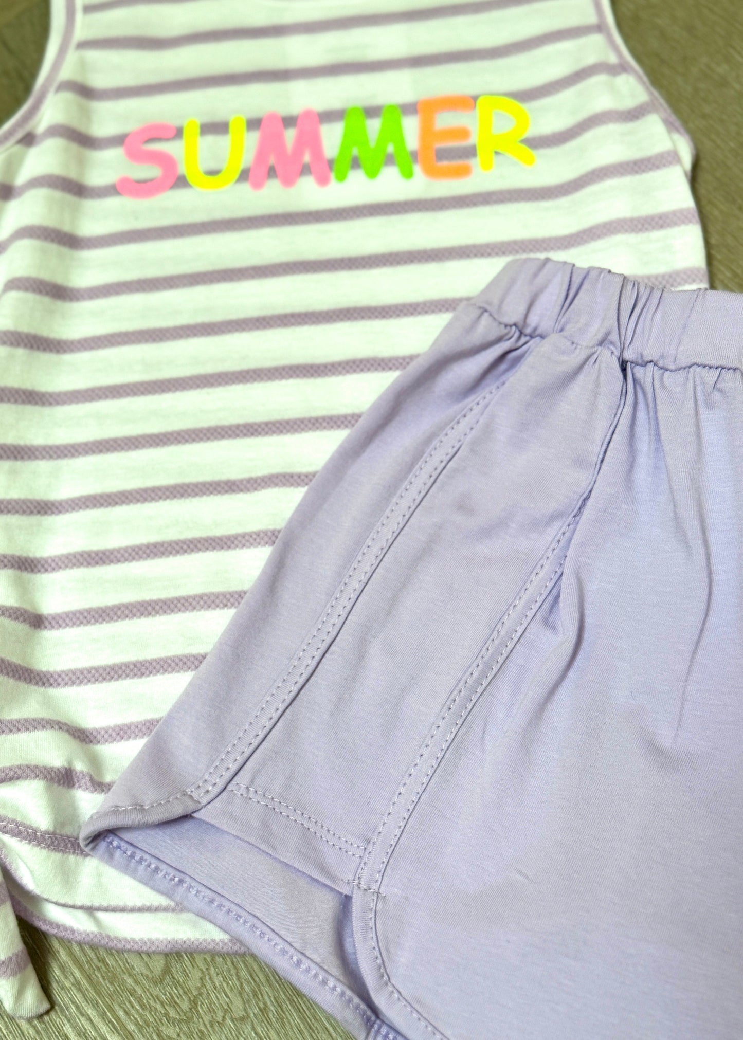 Striped tank top with 'SUMMER' text and a purple skirt on a green surface